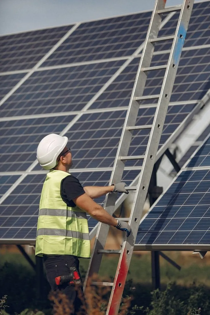 Technician in safety gear working on a solar array